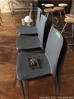 Three gray resin Heller chairs in a row on wooden floor