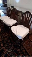 Three chairs side by side upholstered in vinyl with white covers tied on