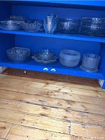 Two-shelf blue unit holding multiple glass items front view