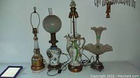 Four lamps in a row: two without shades at left, two with shades at right