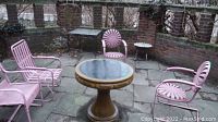 All four pink metal outdoor chairs arranged on a stone patio; styles include perforated, sunburst, horizontal slatted, vertical slatted.