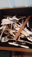 Assortment of mixed utensils in open drawer showing multiple Bakelite-handled knives, servers, spatulas and spoons