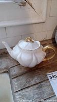 Side angle of white scalloped teapot on wooden surface