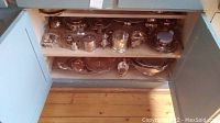 Multiple silver plated items on shelves including shakers, containers, bowls and platters