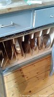 Multiple silver-plated trays stored upright in cardboard separators inside a cabinet