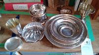 Frontal view of assorted sterling silver pieces including loving cup, creamer on stand, scalloped dish, pepper shaker, and small bowl.