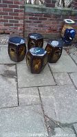 Four hexagonal brown glazed ceramic stools grouped on patio