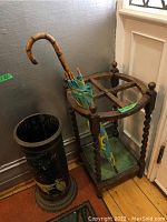 Front view of wooden umbrella stand showing square frame, barley twist posts and green metal tray
