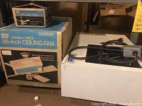 Blue and white Sears box labeled Variable Speed 36-inch Ceiling Fan Model 349050 and small swag kit box on shelf