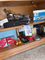 Shelf with various tech items including boxes, cables, black case, and electronics components