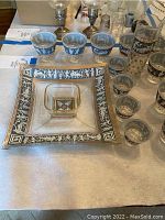 Full view of Egyptian-inspired glassware including large square plate, small bowl, and multiple small painted glasses
