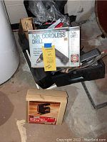 Full view of Black & Decker cordless drill box and Sears Craftsman Sabre Saw box stacked on floor in basement workshop setting