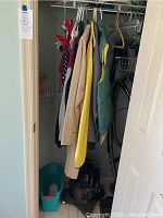 Closet showing men's jackets, various hangers, and a vacuum cleaner at the bottom.