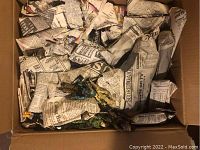 Box packed with crumpled newspaper and visible figures at top