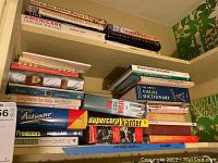 Top shelf with various books on Americans, jewelry, art, fiction, and reference titles including a visual dictionary.