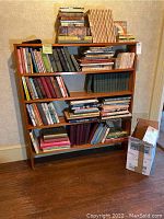 Bookshelf filled with assorted hard and soft bound books, primarily children's and vintage