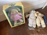Cabbage Patch Kids Flora Wendi doll in original box with two vintage stuffed bears placed next to it on the floor.