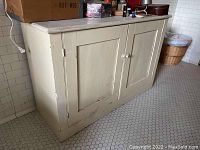 Vintage wood cabinet with two doors, marble top, showing scratches and wear on the finish.