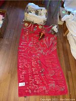 Numerous faceted crystal bead chains and assorted drop prisms laid out on red cloth