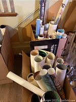 Box filled with multiple rolled posters of different sizes and themes, including natural landscapes and art prints.