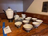Full view of tea set including teapot, sugar bowl, creamer, 8 teacups and saucers arranged on surface