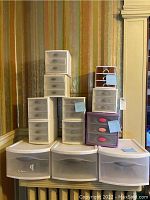 Overall view of all twelve Sterilite plastic storage drawer units stacked together, showing variety of sizes and drawer configurations.