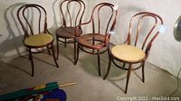 Four vintage bent wood chairs arranged, including one armchair with broken cane seat and cushioned seats with some staining