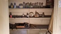 Shelving displaying various jars, glass light shades, and some small household items