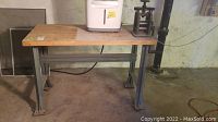 Overall view of workbench showing metal frame, wooden top, and attached tin press