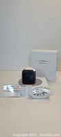 Photo showing the ZKCreation smart watch with white silicone band, two screen protectors, charging cable, and original packaging box.