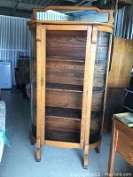 Front view of wooden curio cabinet showing shelves and curved glass side panels, missing middle glass panel.