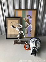 Photo showing the full set: metal sculpture, two framed prints, large ceramic head sculpture, and small ceramic mask sculpture on a flat surface.