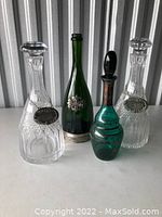 Four assorted decorative decanters as described, arranged upright with visible metal labels and decorative elements.
