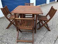 Set of square wood table and four folding chairs assembled outdoors