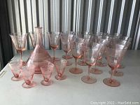 Wide view of all pink depression glass items including decanter and stemware arranged on a table