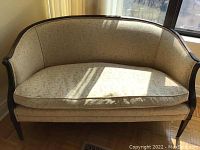 Front view of settee showing upholstered curved back, single seat cushion and wood frame
