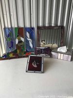 Wide view of all stained glass items showing decorative panels, mirror, tissue box cover, bow tie shaped item, and frame.