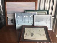 Five framed winter landscape paintings by W. Vance arranged together on a wooden table showing size and condition of frames, wood, green, and silver frames visible.