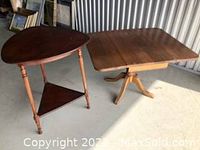 Photo of two wooden tables: one rectangular folding table with drop leaf extensions, one round side table with a triangular lower shelf