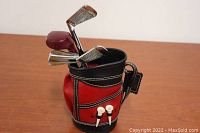 Miniature golf bag holding golf club-style bar tools including teas attached to front