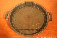 Top view of the cast iron griddle showing the textured cooking surface with handles and a grooved section.