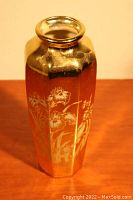 Side view of the vase showing delicate flower and leaf patterns on a gold background.