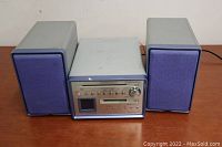 Full view of Kenwood mini audio system with unit and two speakers on either side positioned on a table.