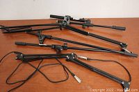 Four black microphone boom arms. One arm has cable running along with an XLR connector visible.