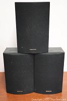 Three Onkyo SKM520S speakers stacked with fabric grills showing the Onkyo logo on the bottom center of each.