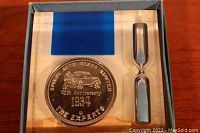 View of commemorative coin and hourglass in display case