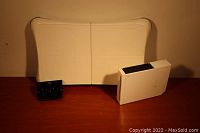 The lot includes a white Nintendo Wii console, a Wii Balance Board, and a small black charging component on a wooden surface.