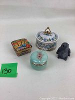 Four assorted trinket items including three boxes and one bird figurine on white background