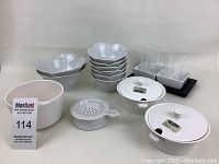 Photo of all bowls and decor arranged showing six scalloped edge bowls stacked, two lidded dishes, ceramic grater, larger bowls, and square bowls on tray with glass container