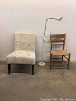 Three-item lot: one upholstered chair with script pattern, one wooden chair, one white reading lamp on floor.